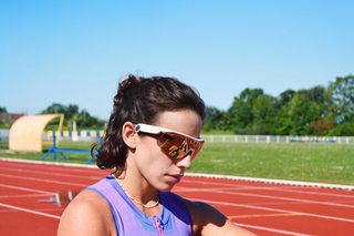 Runner on a track in white-framed sport sunglasses checking her watch